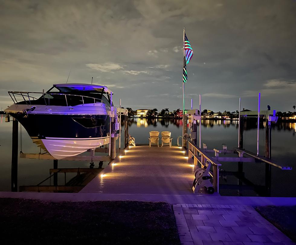 Marina dock at night with warm walkway lighting reflecting on water