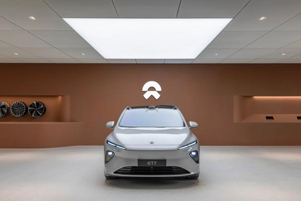Real NIO ET7 electric vehicle displayed in modern showroom with track lighting and brand wall