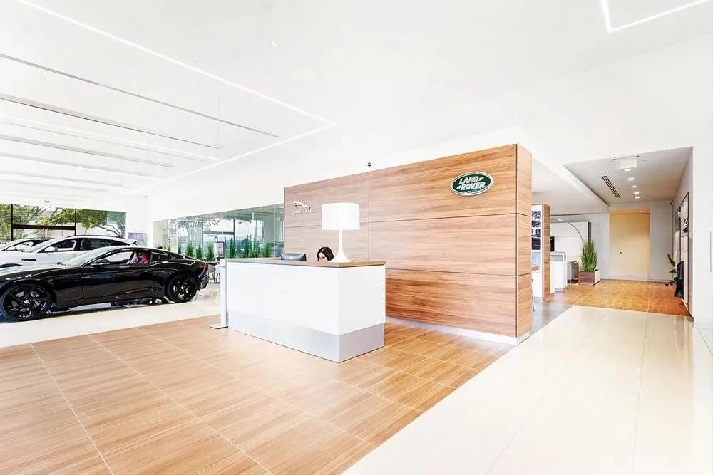 Real Jaguar Land Rover dealership showroom with branded reception desk and visible cars through glass