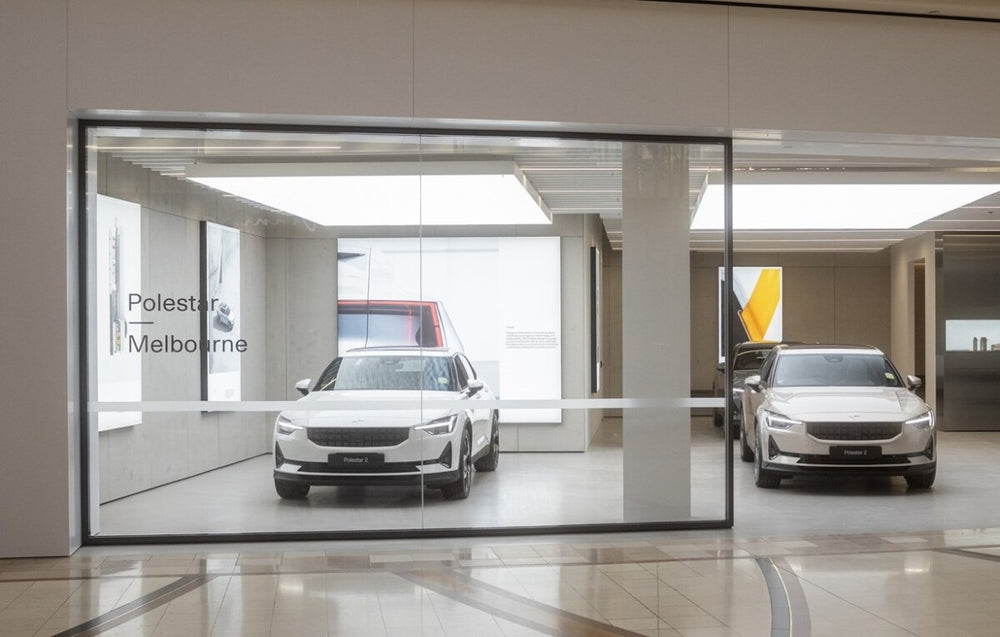 Polestar 2 showroom interior with bright white lighting, minimalist design, and multiple vehicles on display