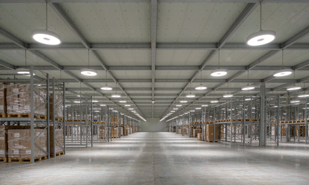 Round LED high-bay luminaires in even rows lighting an open distribution warehouse floor