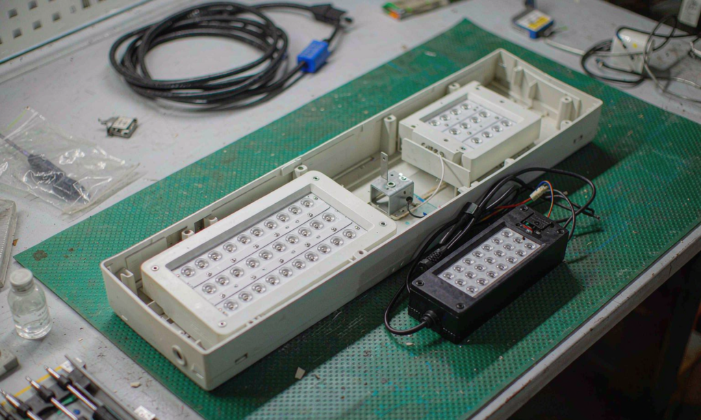 Opened commercial LED luminaire housing with a removable light engine and separate control gear on a workshop bench