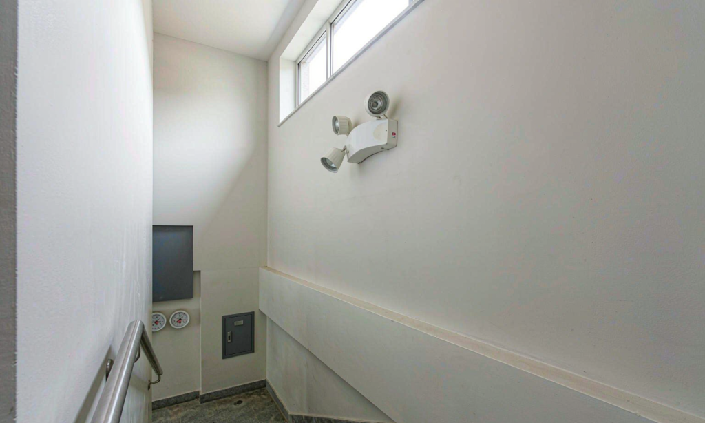 Emergency light unit mounted on the wall of a commercial stairwell