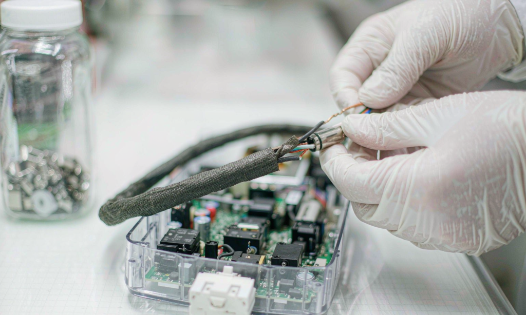 Technician in white gloves inspecting cable insulation and LED driver components on a lab bench